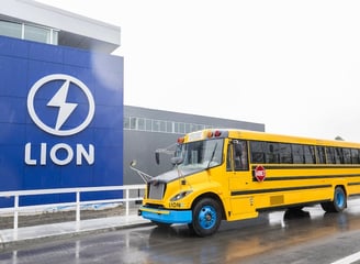 a yellow school bus parked in front of a lion