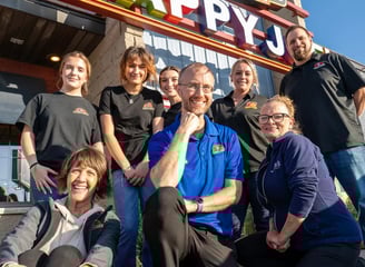 a group of people standing in front of a happy j j's restaurant