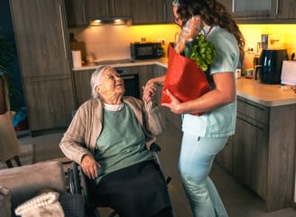 A nurse assists an elderly woman in a wheelchair, providing support and care in a healthcare settin