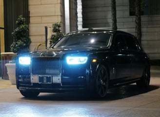 Front side image of a black Rolls Royce parked upon a pavement space