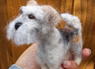 a person holding a small needle felted custom dog