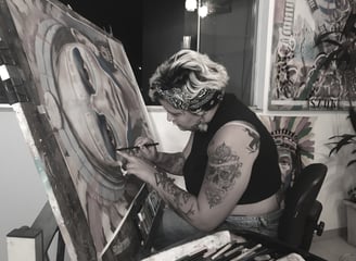 Amanda Amorim no processo de criação de arte usando stencil no estúdio