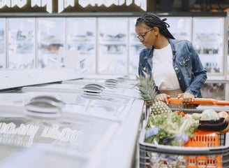 a woman in a denim jacket and jeans standing in a grocery store