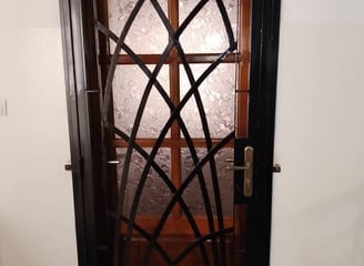 "Porte en métal forgé à motif géométrique, combinant verre texturé et cadre noir
