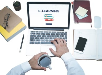 a person sitting at a desk with a laptop and a cup of coffee