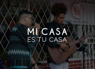 Imagen del día de inauguración de MI CASA, Tienda Multimarca, con dos cantantes locales de fondo y el slogan de la tienda.