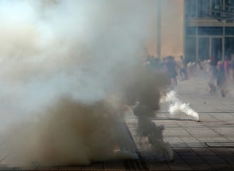 Dūmai plinta per protestą miesto aikštėje, pabrėžiant įtampos ir krizių valdymo svarbą