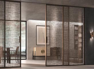 Separación de ambientes con puertas correderas de cristal en espacio cálido con materiales naturales