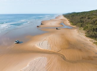 Fraser island beach drone shot, 4WD cars driving on the beach on a sunny day