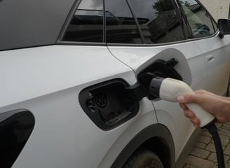 a person plugging in a Tesla EV car to charge from Excess Solar