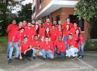 a group of people in red shirts and jeans posing for a group photo