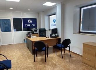 Oficina de AG Seguros - Zurich con escritorio, sillas de atención al cliente y ambiente profesional