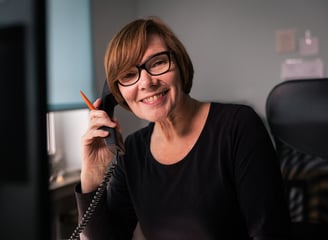 eine Frau in schwarzem Shirt ist in an einem Telefon im Büro