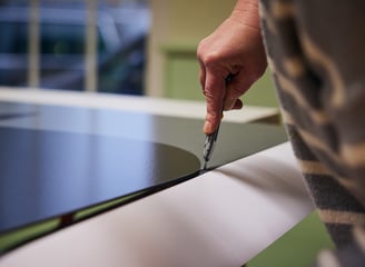 Professioneller Druck auf Alu dibond wird mit einem cutter Messer beschnitten, Hand Hält Werkzeug