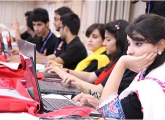 A diverse group of individuals collaborating at a table, each focused on their laptops, engaged