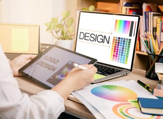 Graphic designer creating a logo design using a tablet and laptop, showcasing Desynco’s expertise in digital graphics.