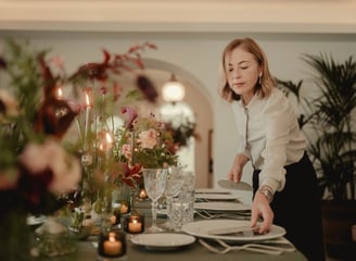 a woman is setting a table with a plate of food