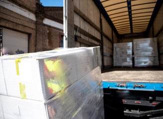 A close-up of palletised shed materials shrink-wrapped and being unloaded from a curtain-side truck
