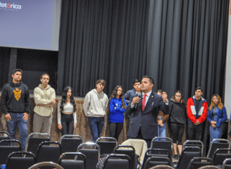 a man in a suit and tie standing in front of a crowd of people
