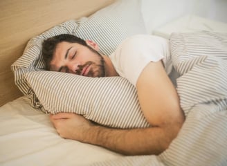Hombre con barba durmiendo plácidamente, abrazando a su almohada