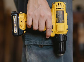 a man holding a cordless drill in his hand