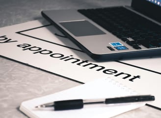 a laptop computer and pen on a desk with the words by appointment