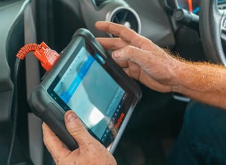 a man holding a car diagnostic computer in his hand