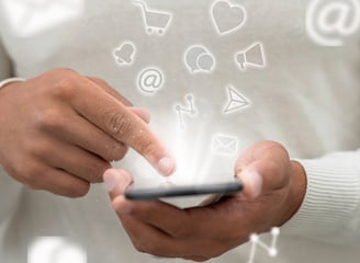 Pessoa segurando um celular, com ícones de redes sociais flutuando