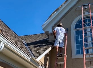 Professional Painter Working on a Large House with Exterior Painting and Rotten Gutter Replacement