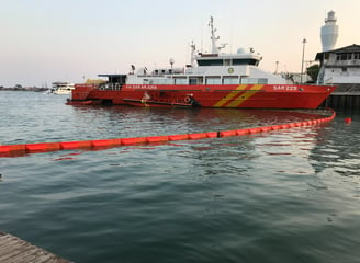 a boat in the water with Oil Boom in water