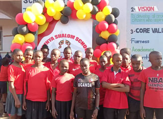 a group of young children in red shirts and black shorts