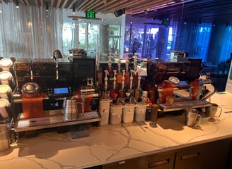 Two Mastrena II super-automatic espresso machines set up at a Starbucks barista station with syrups 