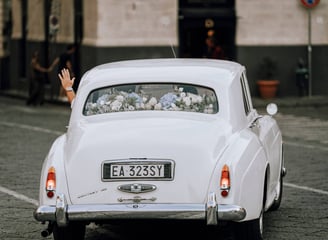 mano che saluta dello sposo, mentre va via con una macchina d'epoca