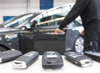 a man standing in front of a car with a bunch of keys