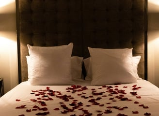 Bett mit Rosenblüten bedeckt