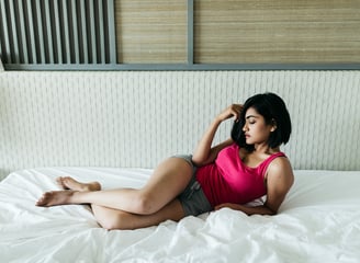 a Sl Ad woman in a pink tank top laying on a bed