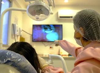 a woman in a hospital room with showing the patients teeth on the screen