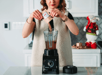 mujer preparando un batido usando una licuadora negra