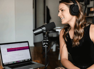 Mujer con audifonos y micrófono grabando un podcast
