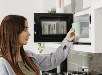 mujer calentando una taza en un microondas