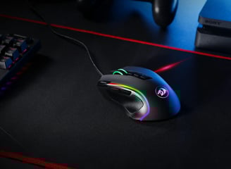 ratón gaming negro con RGB sobre una mesa negra y un teclado