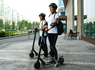 dos mujeres usando patinetes electricos en la calle
