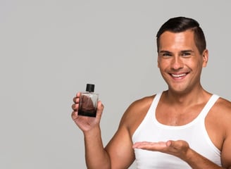 Hombre con playera blanca presentando un perfume