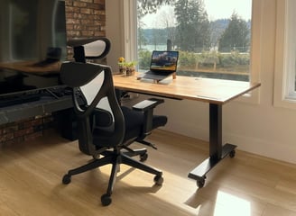 oficina con mesa de madera, una laptop y silla negra ergonomica
