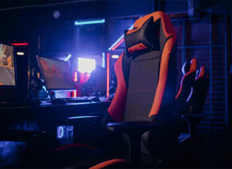Silla Gaming con un escritorio en el fondo y pantallas de PC