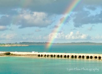 a brightly colored rainbow over a rainbow over the ocean and bridge