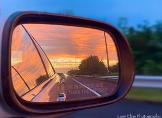 a car's side view of a car's side view mirror with bright orange sunset in it