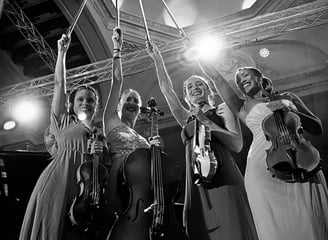 a group of women in dresses and hats holding violin instruments