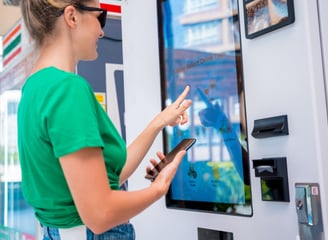 a woman in a green shirt is standing in front of a vending machine