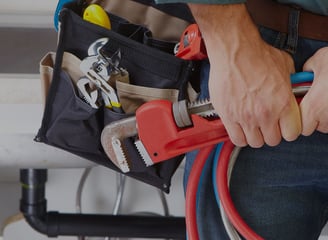 a man in a blue shirt holding a hose and a wrenet